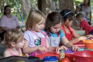 Children wearing aprons putting together quesadillas.