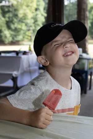 Little boy eating a popsicle makes a funny face.